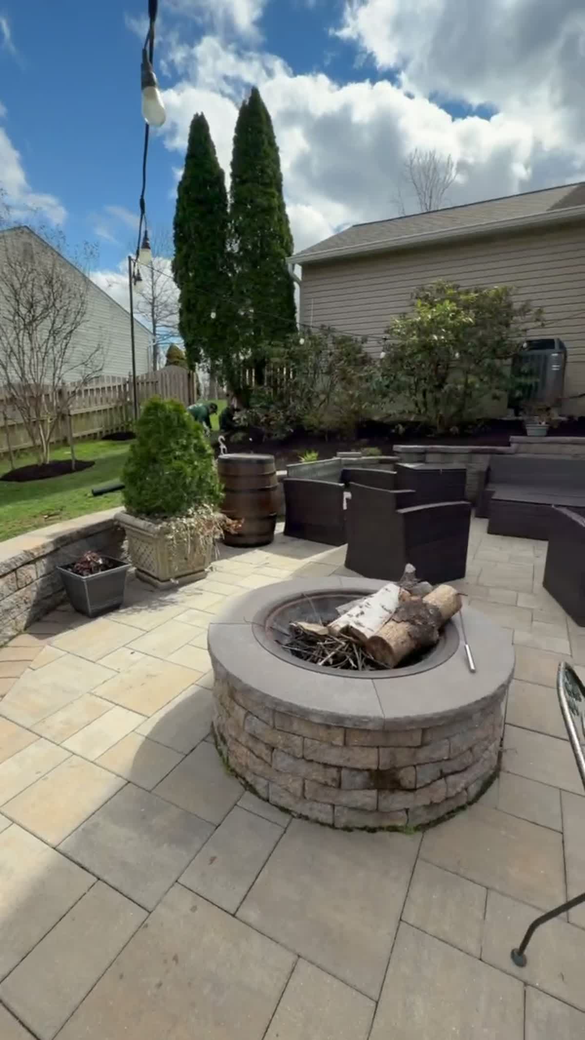 Paver patio with built-in stone fire pit and retaining wall seating built by Green Diamond